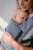 Modelka nosi dziecko w ergonomicznym nosidle KAVKA multi-age ink twill - niebieskie nosidlo z delikatnym wzorem w jodelke (a blue carrier with a twill delicate herringbone pattern)