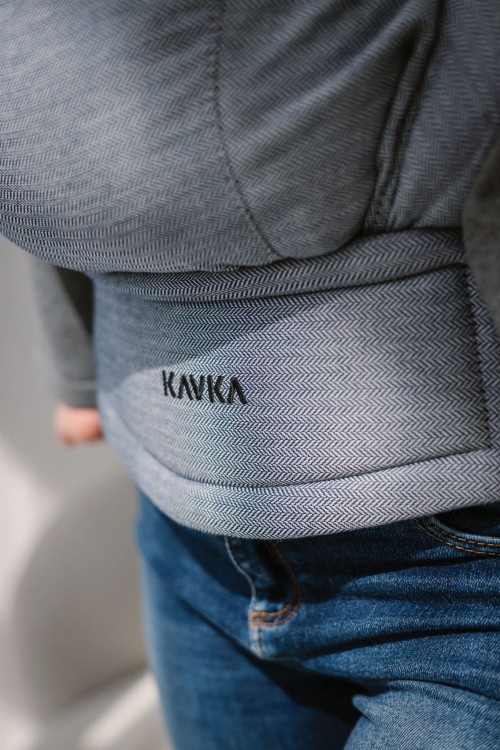 Modelka nosi dziecko w ergonomicznym nosidle KAVKA multi-age ink twill - niebieskie nosidlo z delikatnym wzorem w jodelke (a blue carrier with a twill delicate herringbone pattern) pas biodrowy